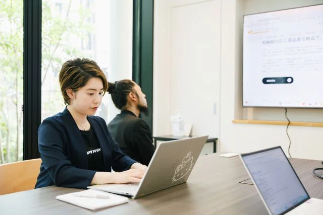 会議室でノートパソコンを使用しながら業務に取り組む社員の様子。