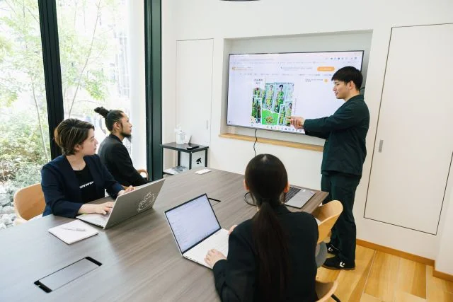 会議室のモニターを使って社員がプレゼンテーションを行い、メンバーで打ち合わせをする様子。